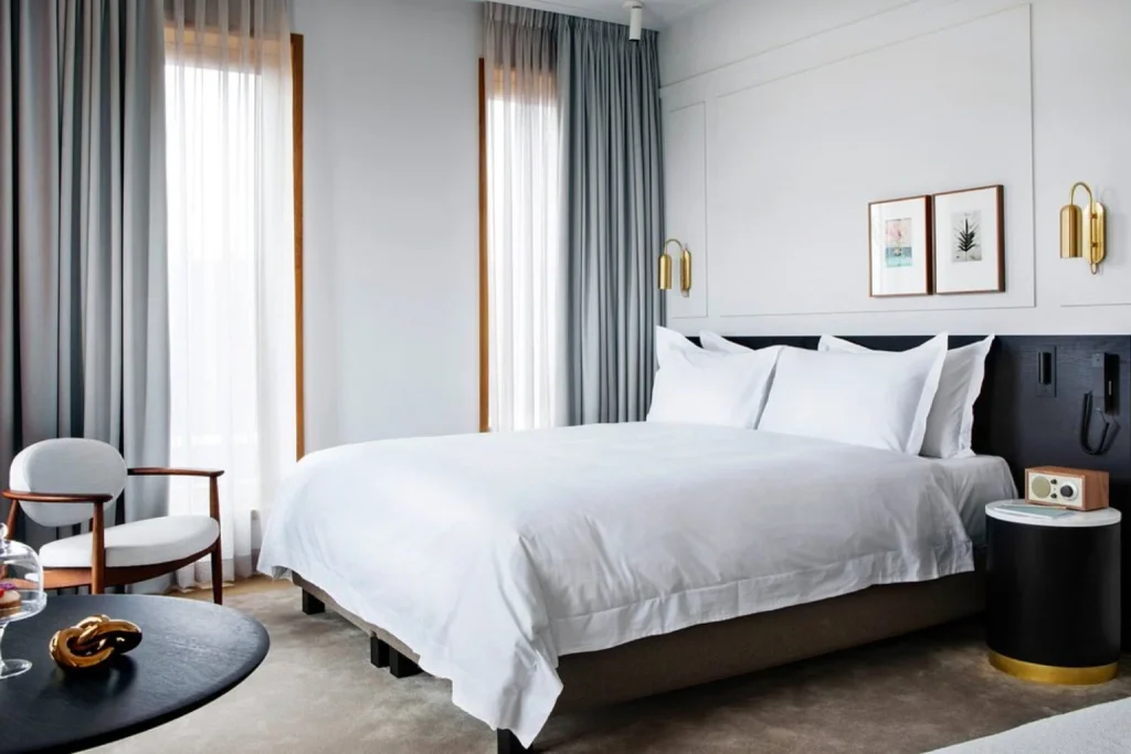 Refined hotel bedroom featuring a king-size bed, contemporary furnishings, soft neutral tones and floor-to-ceiling windows at Pillows Grand Boutique Hotel Maurits at the Park, Amsterdam.