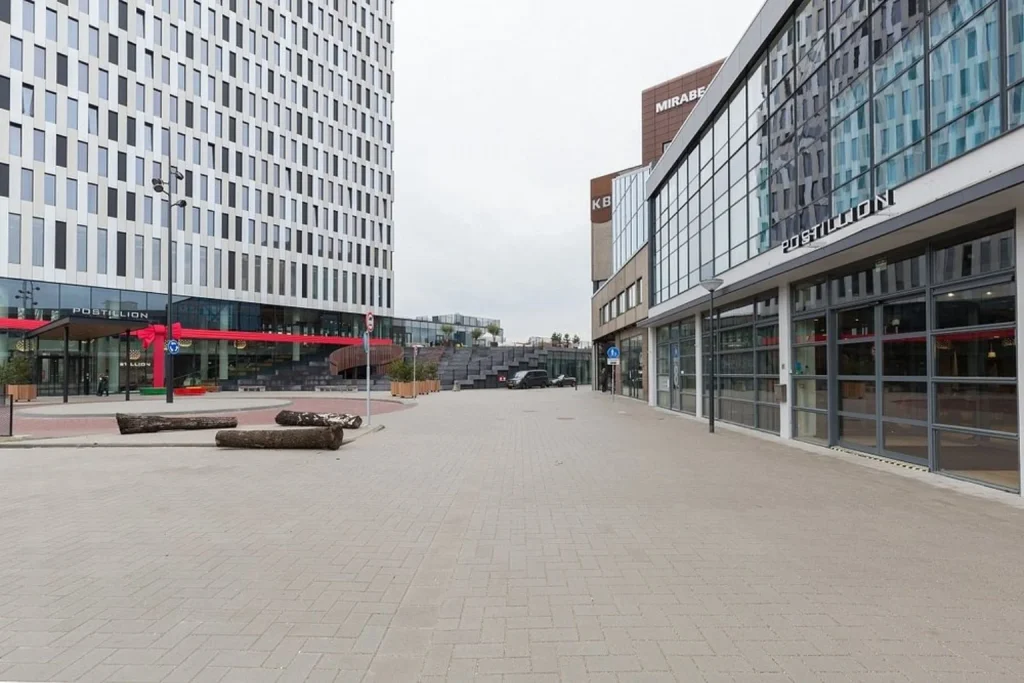 A contemporary glass-fronted hotel building with a spacious entrance plaza and modern urban architecture, Postillion Hotel Amsterdam, Amsterdam.