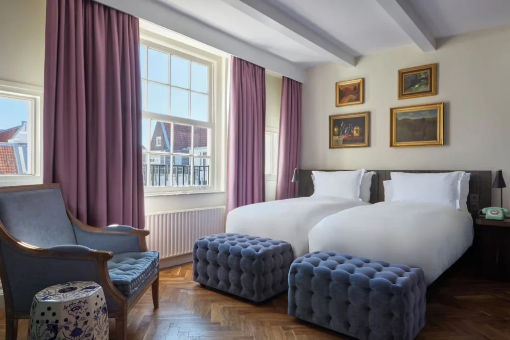 Elegant twin room with large windows and classic furnishings at Pulitzer Amsterdam