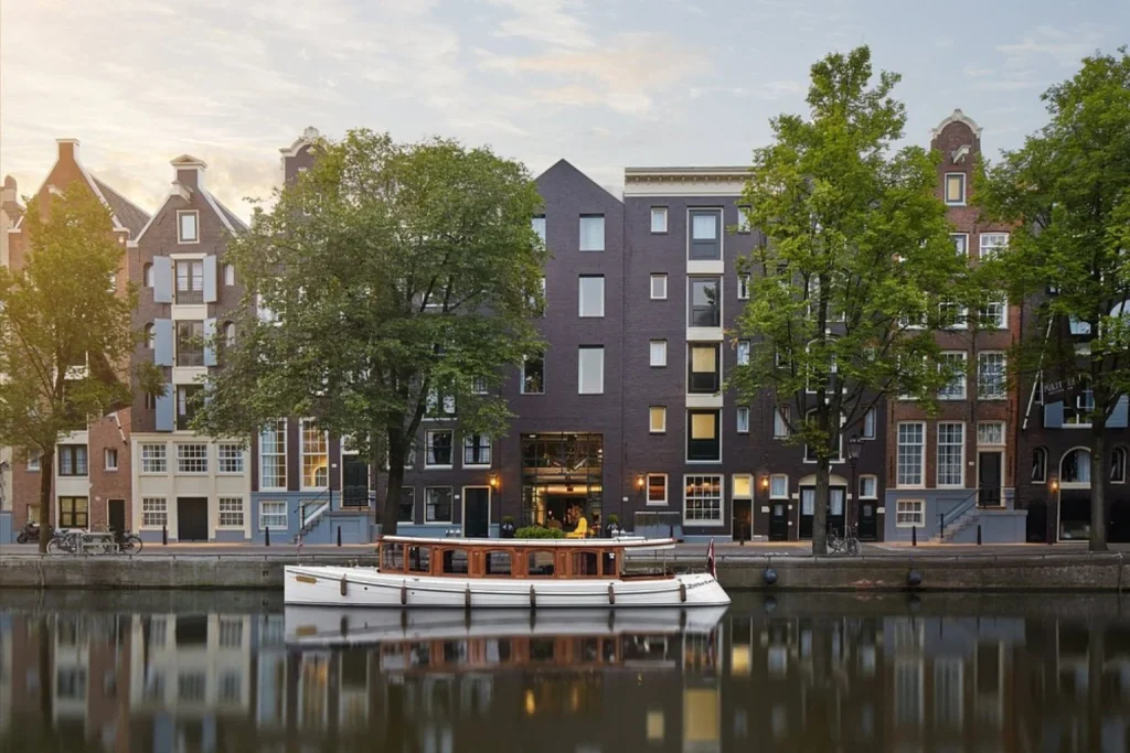 Historic canal houses with a classic boat reflected in the water, Pulitzer Amsterdam, Amsterdam
