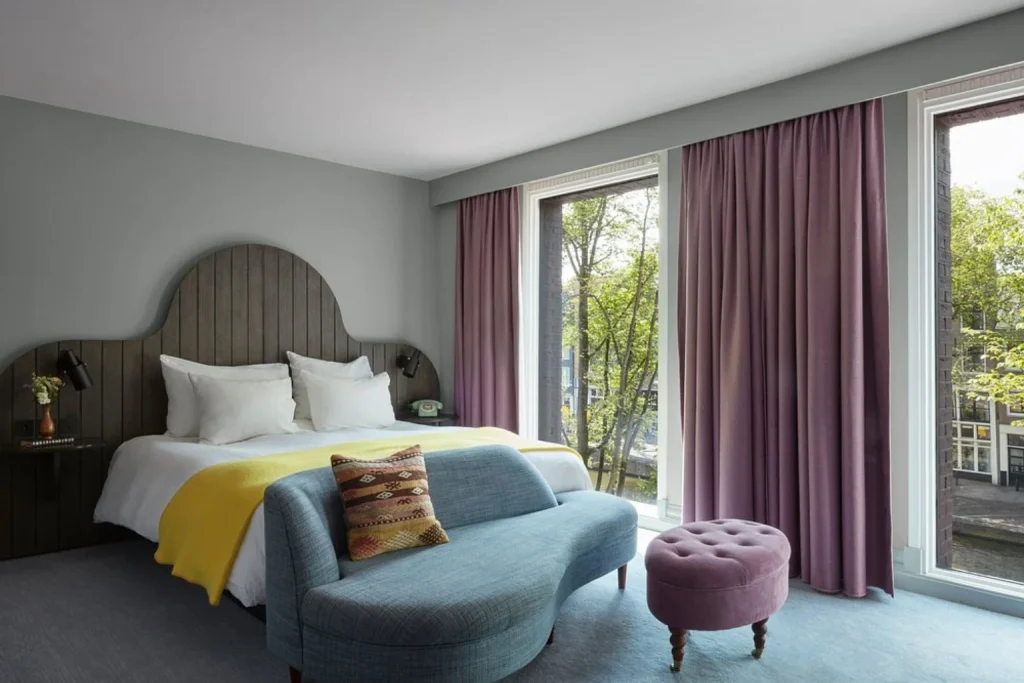 Contemporary guest room with elegant furnishings and large windows overlooking the canal at Pulitzer Amsterdam.