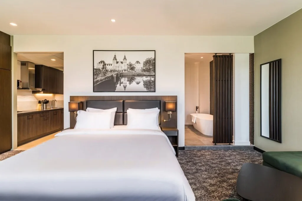 Spacious suite with king bed, kitchenette and open bathroom with bathtub at Radisson Hotel & Suites Amsterdam South, Amsterdam