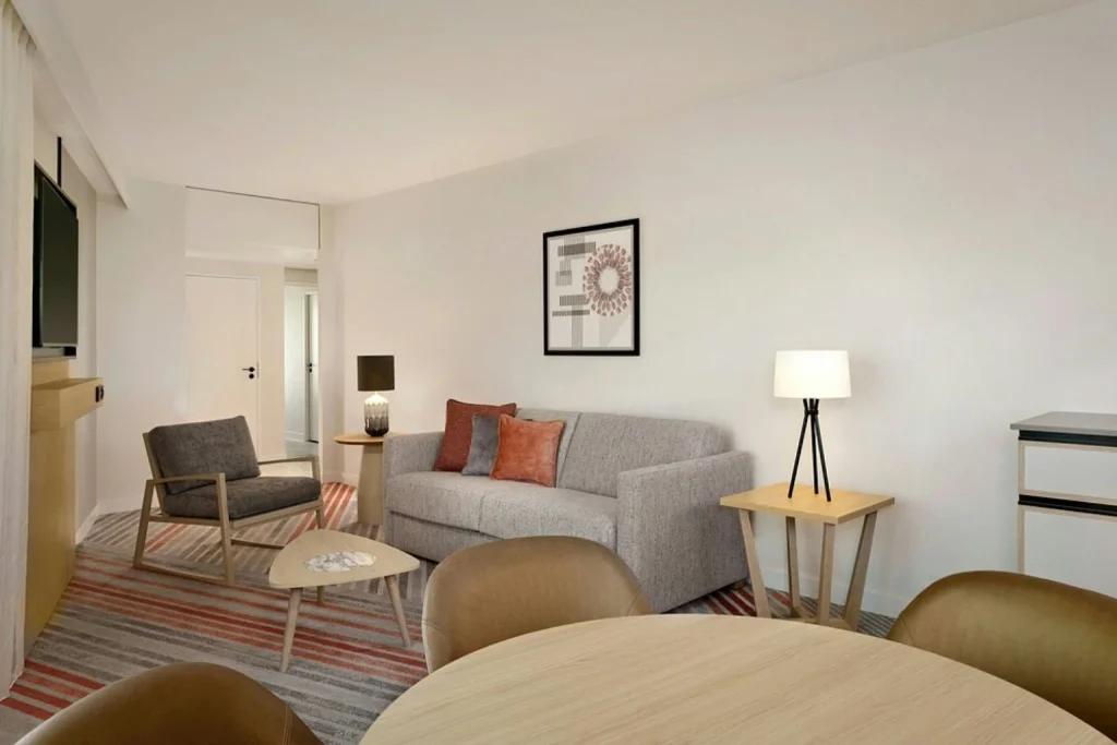 Bright suite at Sheraton Amsterdam Airport featuring a separate living area with sofa, lounge seating and a dining table.