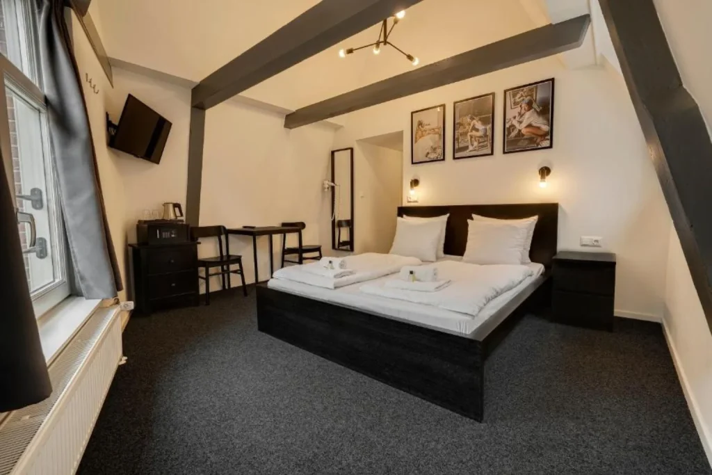 Double room with exposed ceiling beams, a comfortable bed, and modern furnishings in Amsterdam