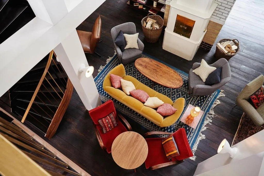 Stylish lounge with colorful seating, patterned rugs and fireplace at The Hoxton Amsterdam West, Amsterdam