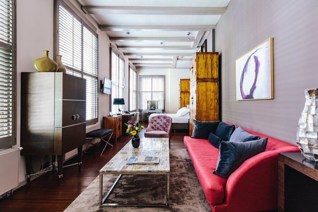 Stylish luxury suite with red sofa, contemporary furnishings and large windows at The Dylan Amsterdam