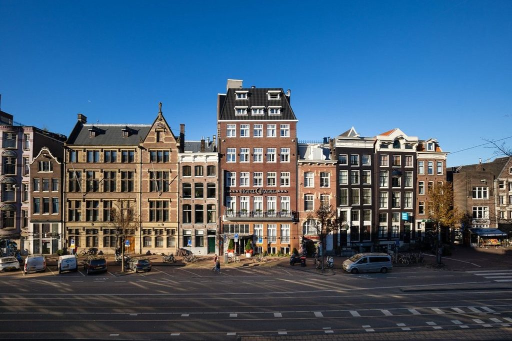 Historic hotel exterior among traditional narrow buildings along a central Amsterdam street at The Highlander Amsterdam.