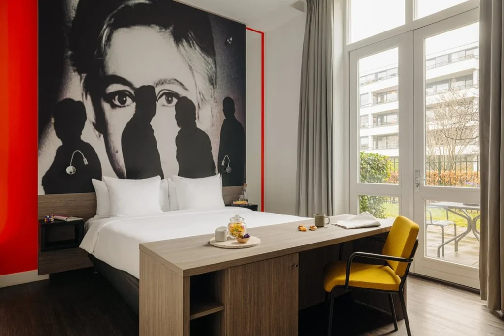 Modern guest room with private balcony and large windows at The Manor Amsterdam
