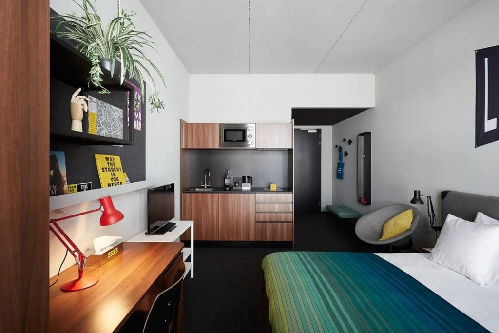 Contemporary guest room with kitchenette, work desk and colorful interior at The Social Hub Amsterdam City.