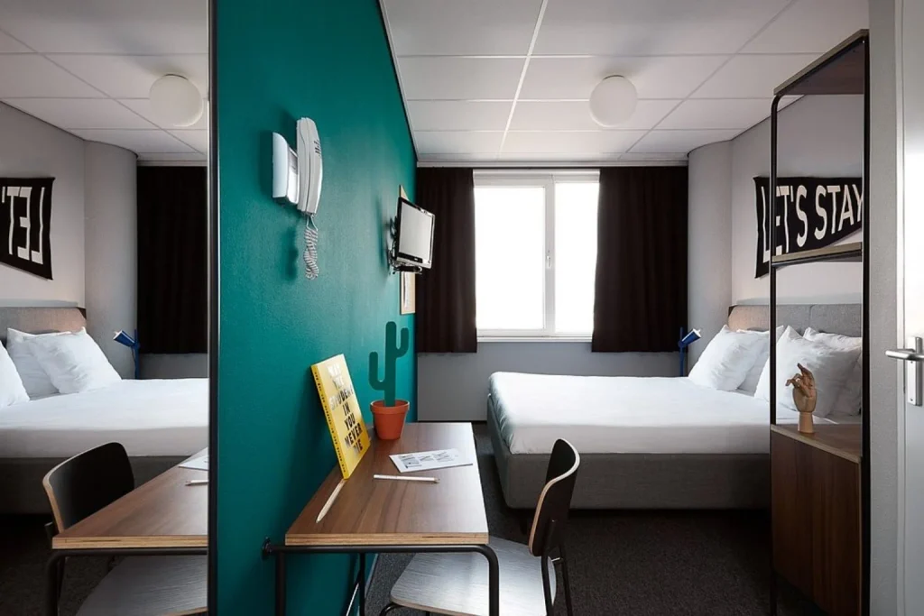 Contemporary guest room at The Student Hotel Amsterdam West featuring a comfortable double bed, dedicated workspace and colorful modern design.
