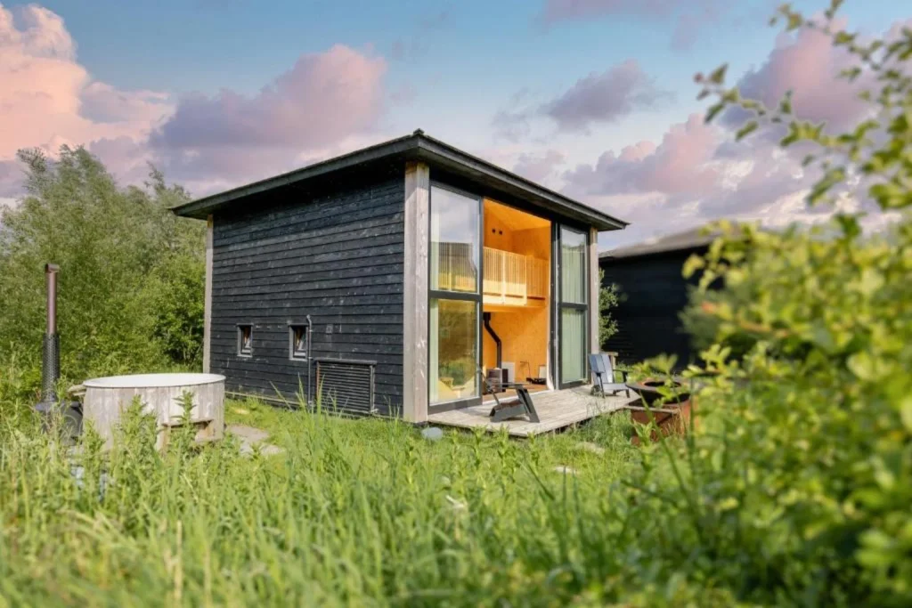Modern private chalet surrounded by greenery with an outdoor wood-fired hot tub at The Unbound Amsterdam.