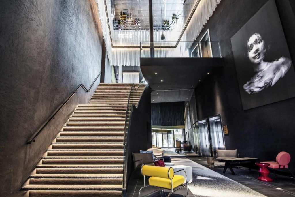 Contemporary lobby with a dramatic illuminated staircase and colorful seating at Tribe Amsterdam City.