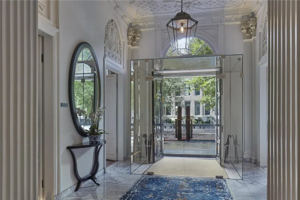 Refined marble entrance with classical details and a view toward the canal at Waldorf Astoria Amsterdam.