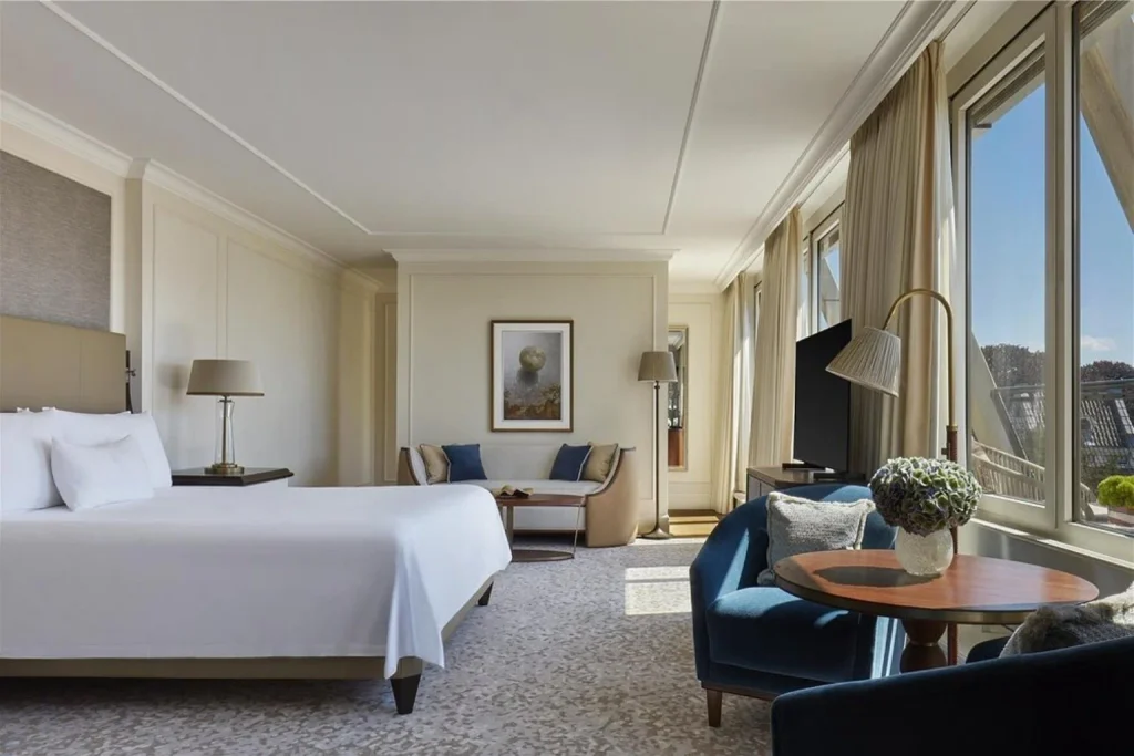 Bright luxury bedroom with king bed, elegant seating area and large windows at Waldorf Astoria Amsterdam