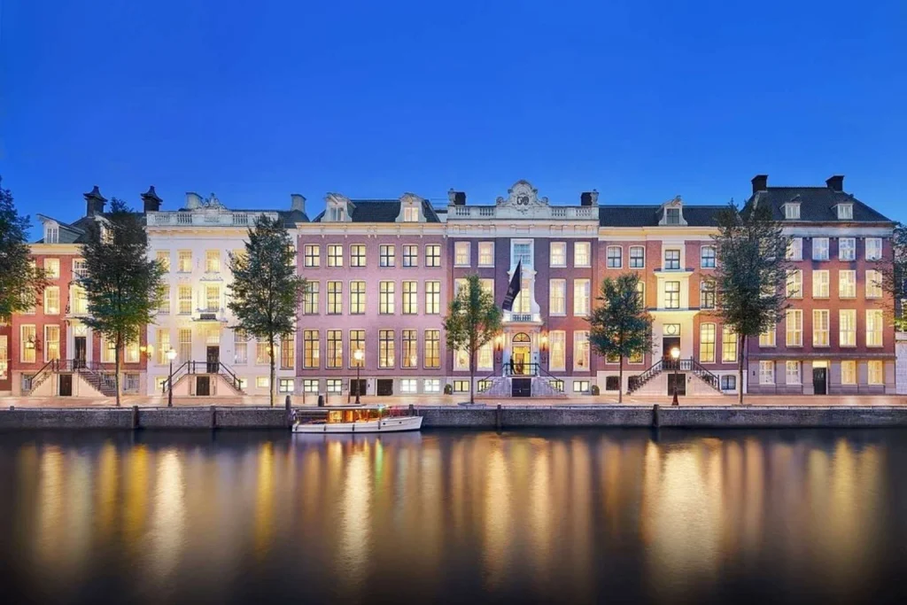 Elegant historic canal houses illuminated at dusk and reflected in the water, Waldorf Astoria Amsterdam, Amsterdam