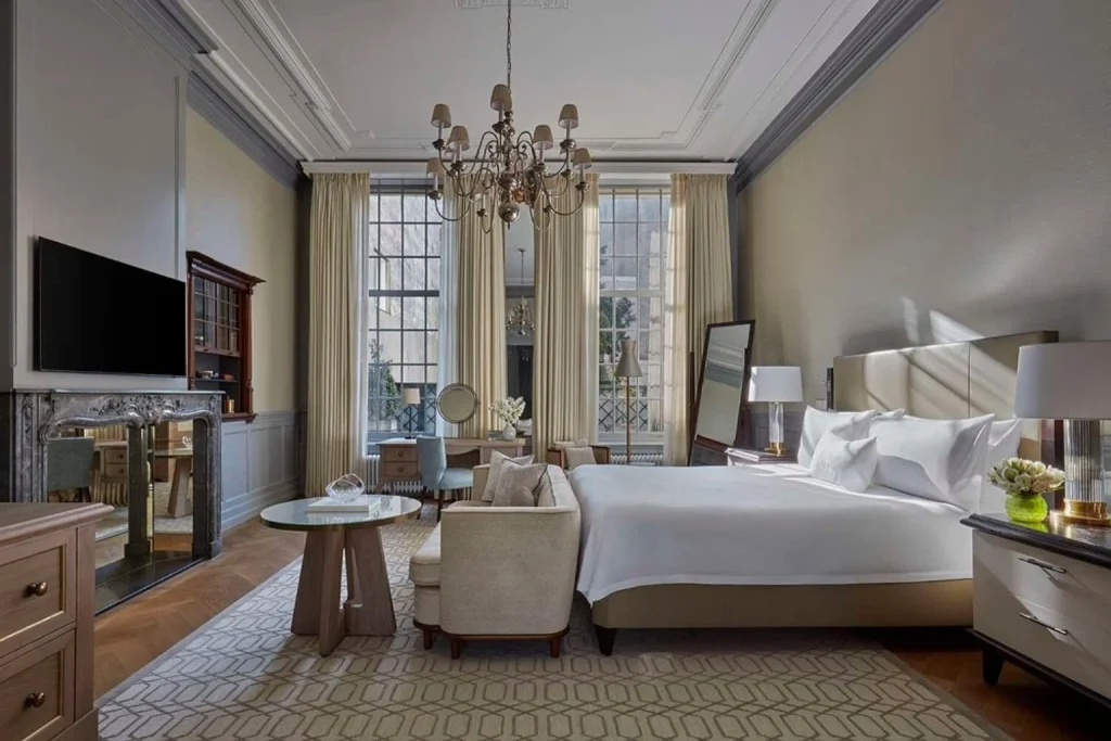 Sophisticated guest room with high ceilings, elegant chandelier and luxurious furnishings at Waldorf Astoria Amsterdam.