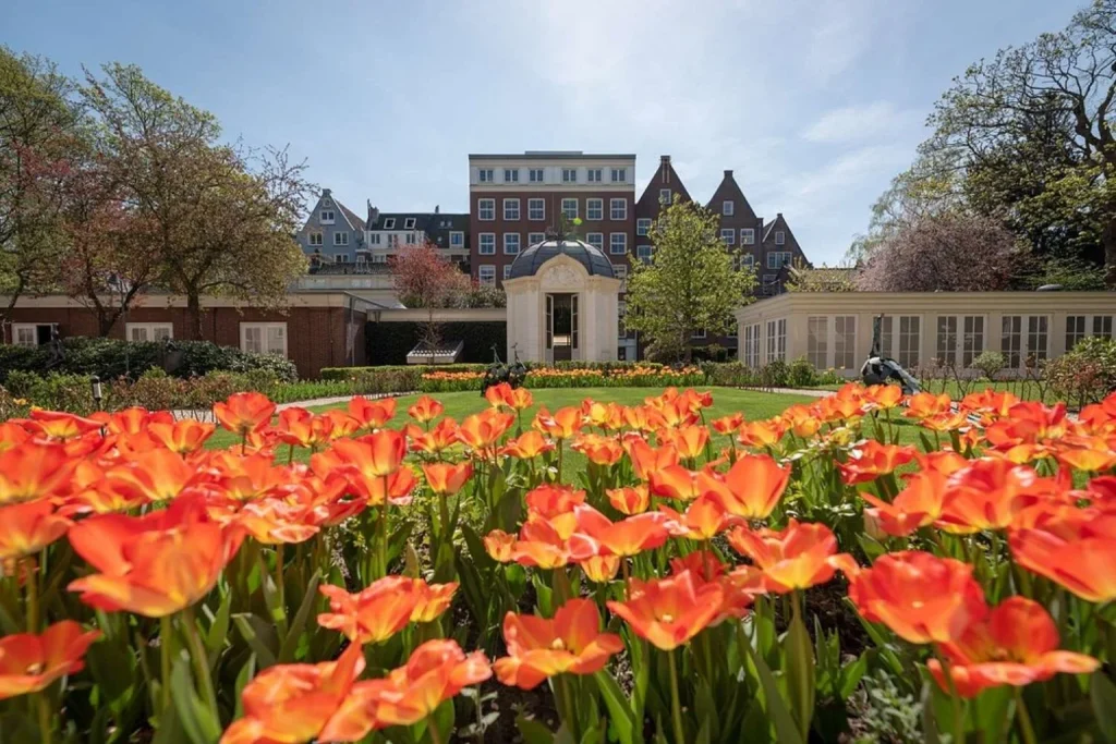 Colourful spring garden with blooming tulips framed by historic Amsterdam architecture, Waldorf Astoria Amsterdam