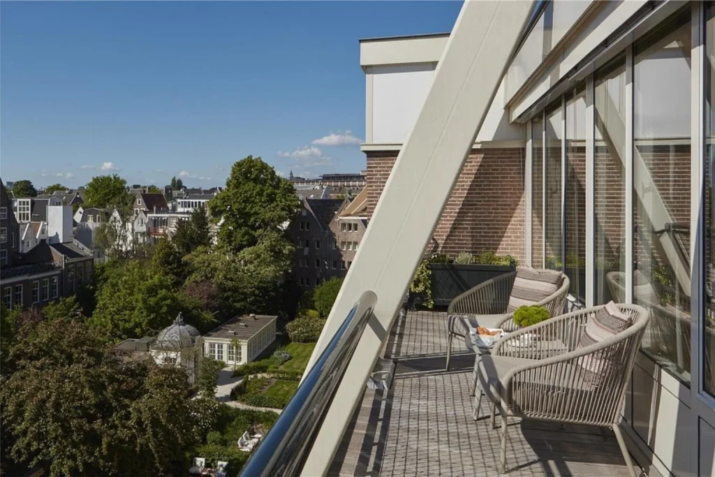 Private terrace overlooking historic rooftops and a peaceful garden at Waldorf Astoria Amsterdam.