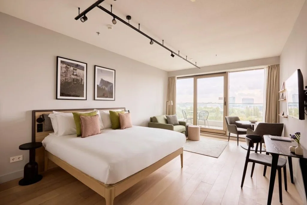 Bright studio at Wilde by Staycity Amsterdam-Noord featuring a large bed, seating and dining areas, and floor-to-ceiling windows