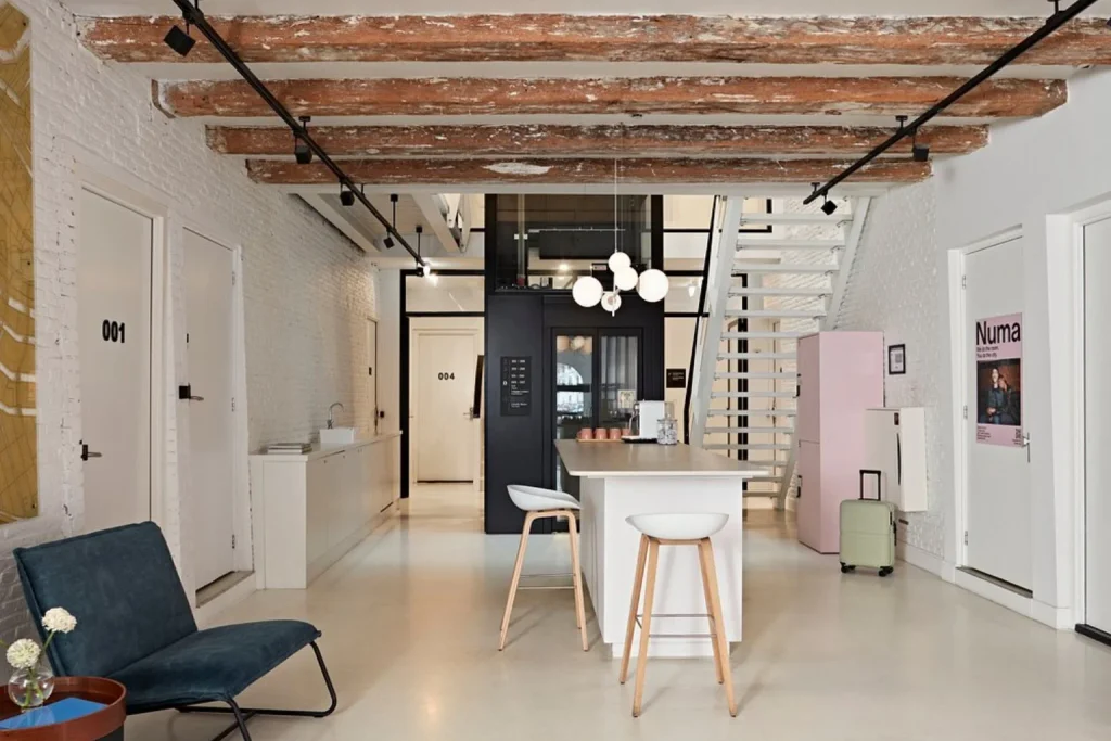 Stylish communal space at YAYS Amsterdam Salthouse Canal with exposed wooden beams, contemporary furnishings and a shared kitchen area