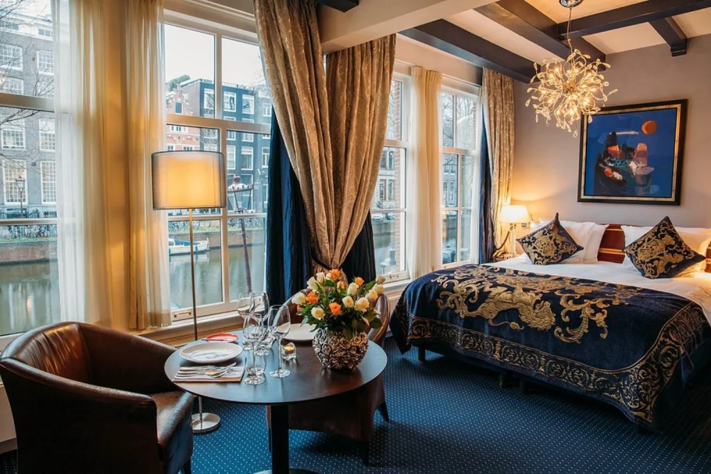 Elegant guest room with ornate décor and large windows overlooking the canal at Ambassade Hotel, Amsterdam