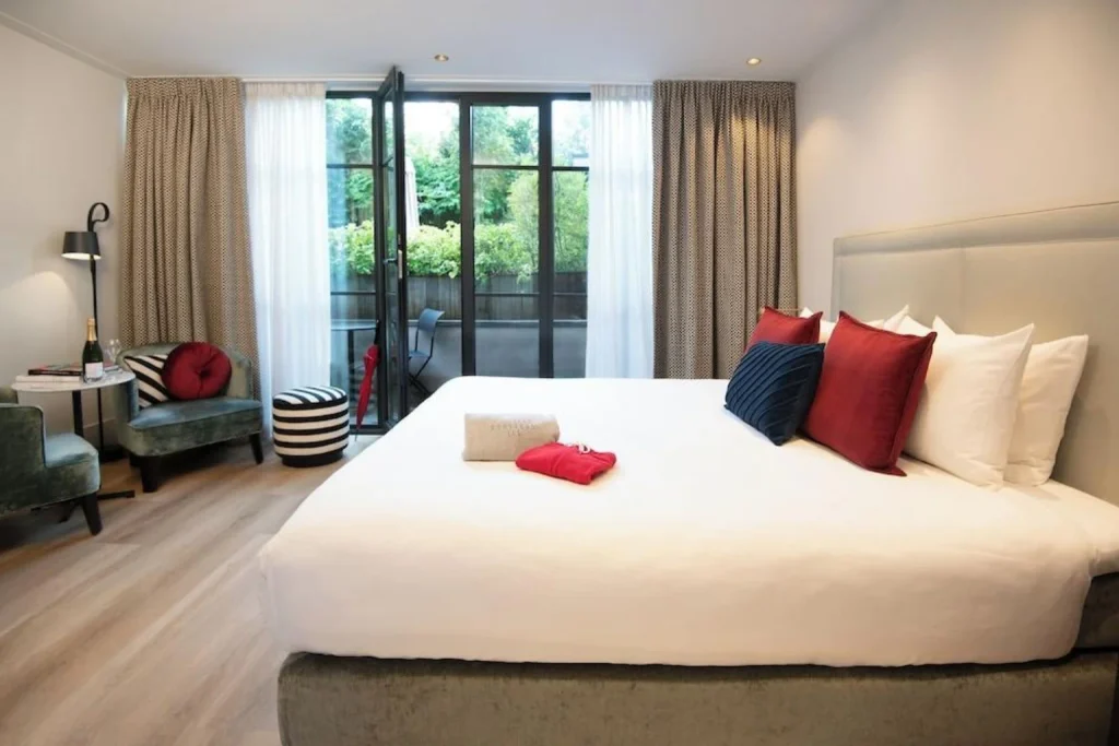 Bright boutique hotel room with a king bed, seating area and private garden terrace at Anna Van Den Vondel Amsterdam, Amsterdam