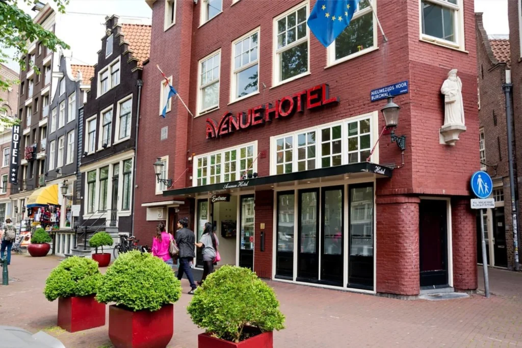 Traditional red-brick hotel building with street-side greenery in central Amsterdam at Avenue Hotel.
