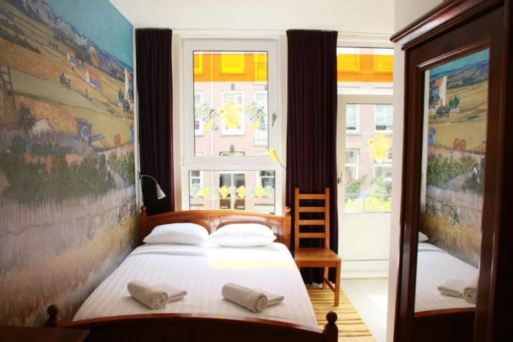 Cozy double room with colorful wall murals, wooden furnishings and plenty of natural light at Bicycle Hotel Amsterdam, Amsterdam