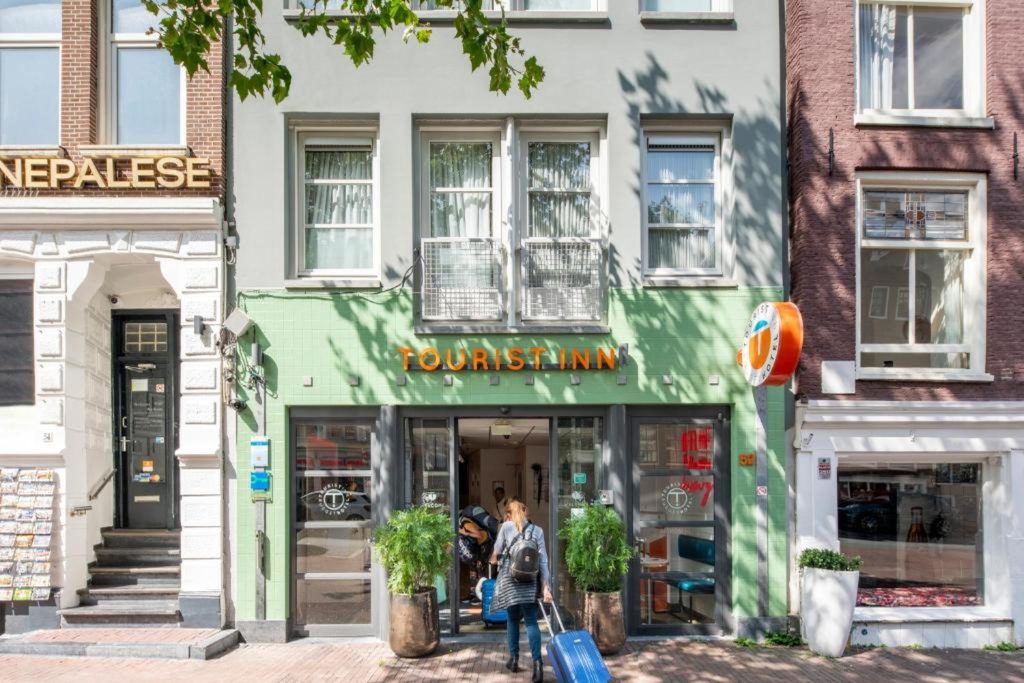 Affordable city centre hotel with a distinctive green façade, street-level entrance and traditional Amsterdam surroundings at Budget Hotel Tourist Inn in Amsterdam.