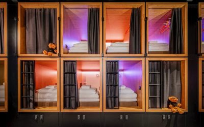 Stacked wooden sleeping pods with privacy curtains and colorful lighting at BUNK Hotel Amsterdam, Amsterdam, Netherlands