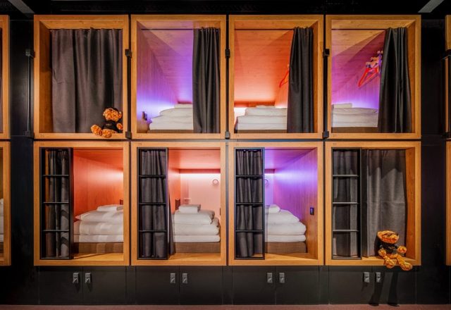 Stacked wooden sleeping pods with privacy curtains and colorful lighting at BUNK Hotel Amsterdam, Amsterdam, Netherlands
