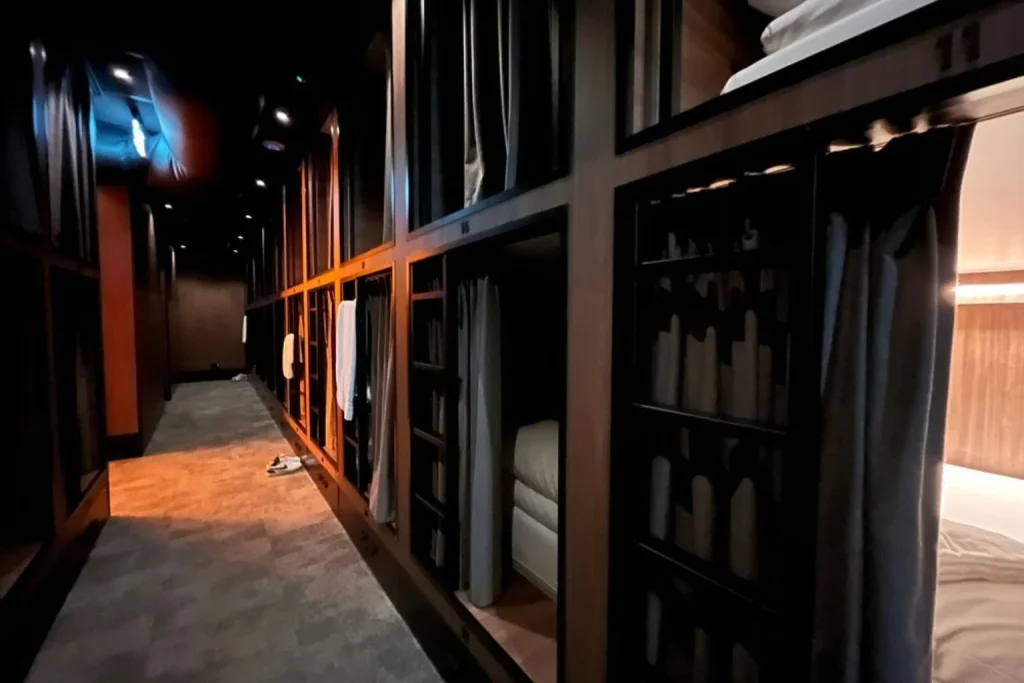 Dark capsule-style sleeping area with stacked private cabins and privacy curtains at Cabins Hotel Amsterdam, Amsterdam, Netherlands