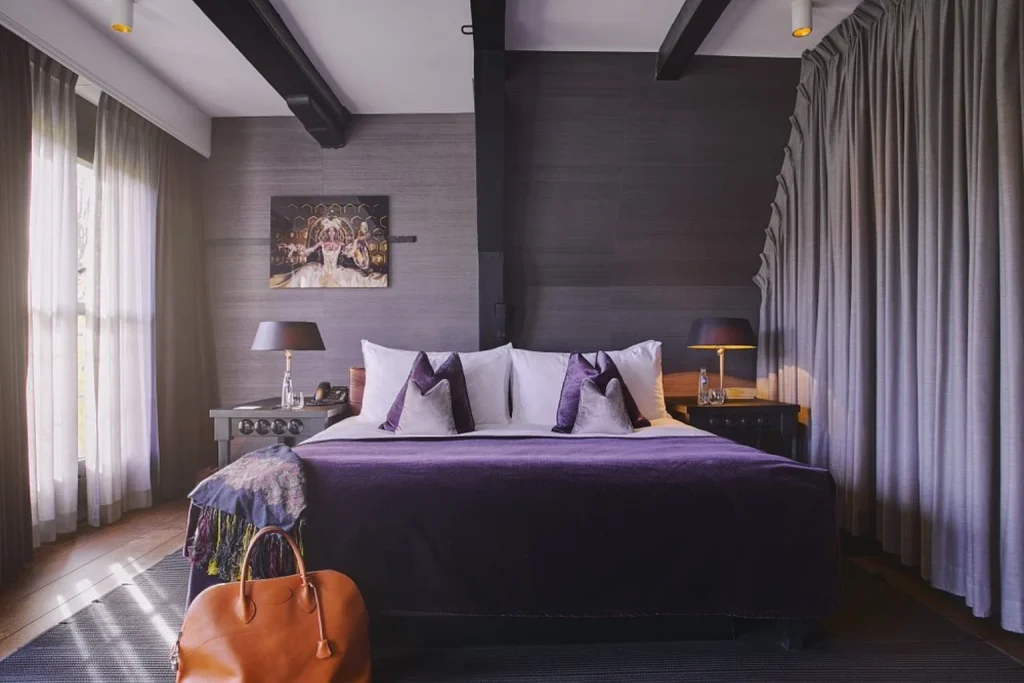 Elegant bedroom with a king-size bed, dark wood details and rich purple accents at Canal House, Amsterdam, Netherlands