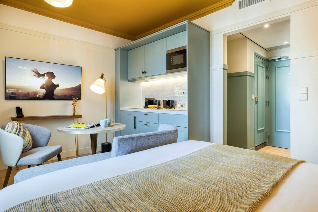 Modern studio room with double bed, kitchenette, dining table and seating area at Citadines Canal Amsterdam, Amsterdam