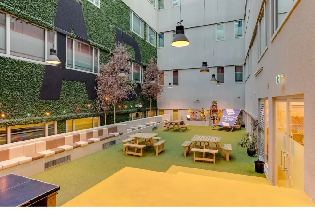 Colorful indoor courtyard with picnic tables and lounge seating at ClinkNOORD Amsterdam