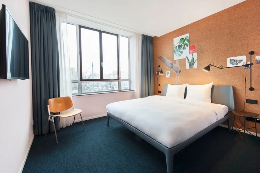Bright modern guest room with a double bed, large windows and stylish eco-conscious interior at Conscious Hotel The Tire Station, Amsterdam