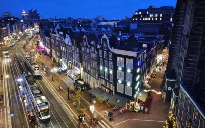 Evening city view around Corner House Amsterdam, with historic Dutch buildings, illuminated streets and trams in central Amsterdam.
