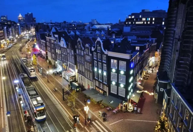 Evening city view around Corner House Amsterdam, with historic Dutch buildings, illuminated streets and trams in central Amsterdam.