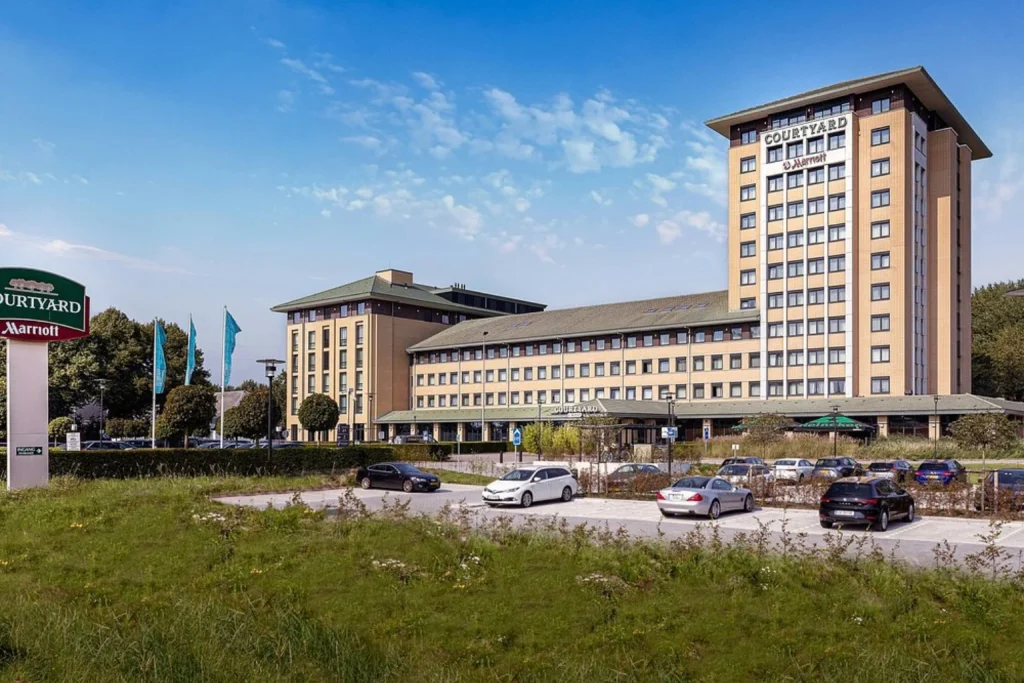 Large airport hotel exterior with parking area and modern tower at Courtyard by Marriott Amsterdam Airport in Amsterdam