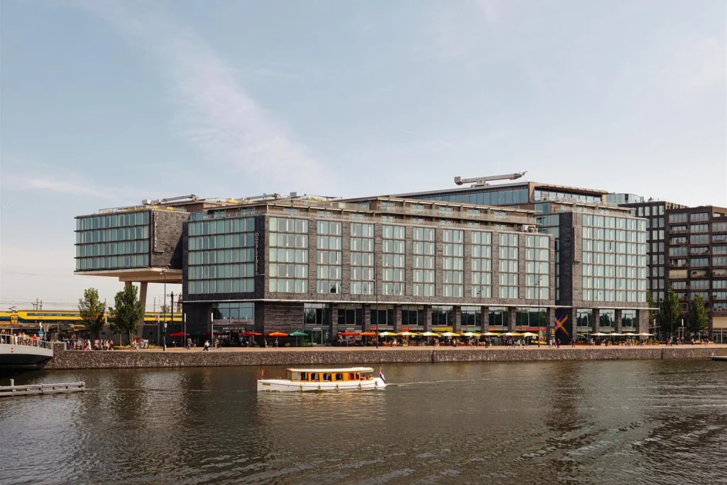 Waterfront exterior of DoubleTree by Hilton Amsterdam Centraal Station with a canal boat in Amsterdam