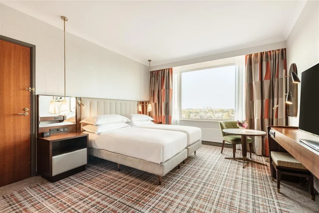 Bright modern guest room with twin beds and city views at Hilton Amsterdam, Amsterdam