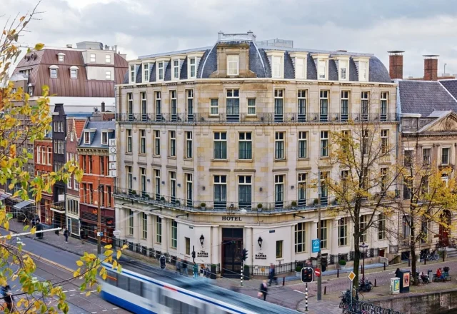 Classic Amsterdam architecture beside the canal with trams passing along the lively city street, Banks Mansion Hotel Amsterdam