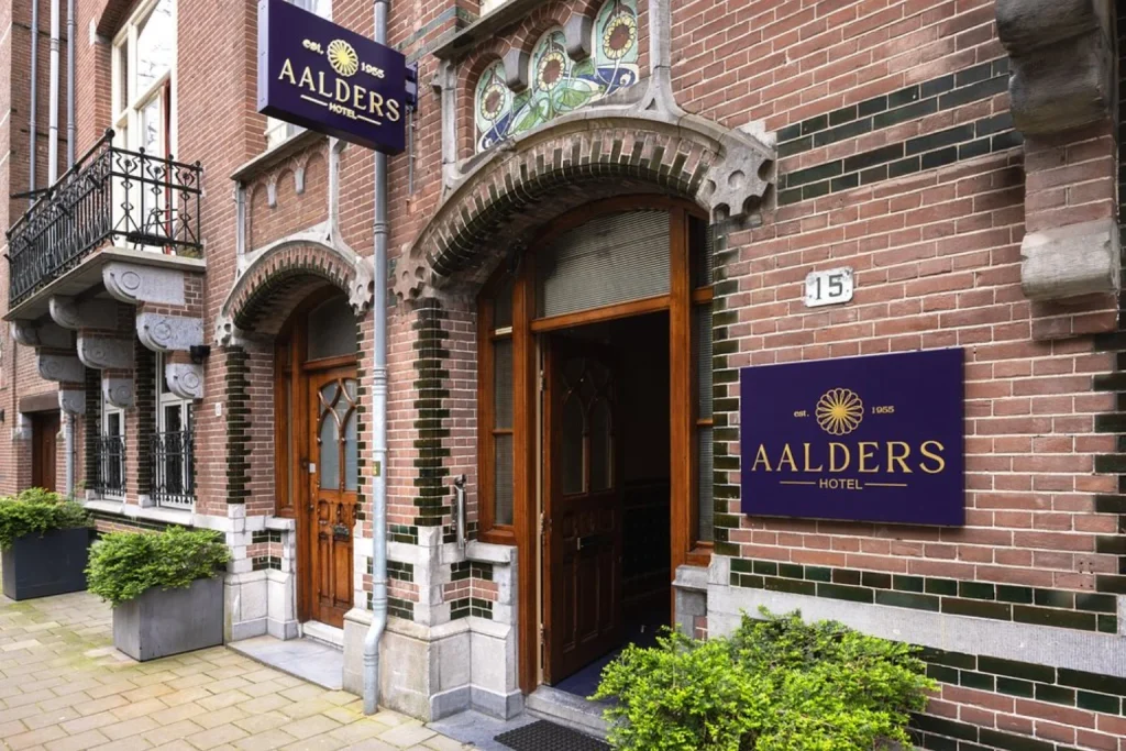 Main entrance featuring a historic brick facade, decorative stonework and traditional architectural details at Hotel Aalders Amsterdam.