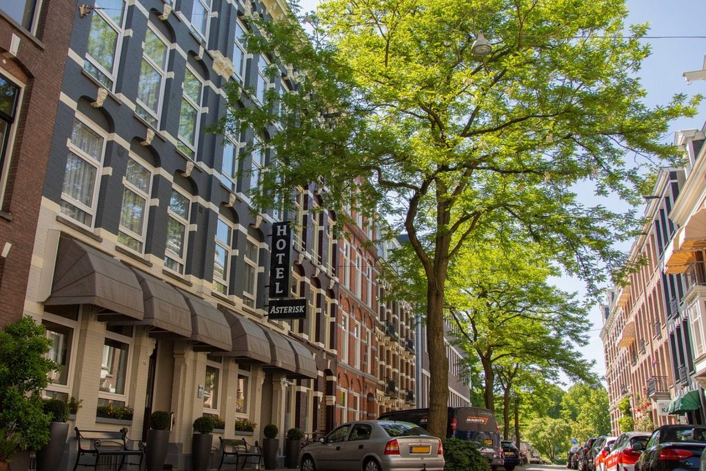 Tree-lined street with traditional Dutch buildings and the entrance to Hotel Asterisk, Amsterdam