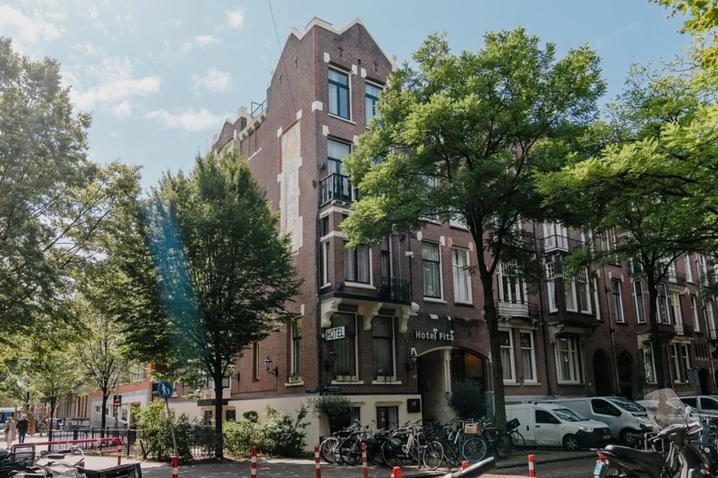 Traditional Amsterdam architecture surrounded by mature trees and bicycles on a quiet street at Hotel Fita Amsterdam, Amsterdam