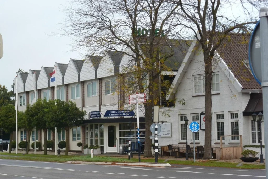 Charming gabled hotel exterior and main entrance along a tree-lined street at Hotel Herbergh Amsterdam Airport in Amsterdam.