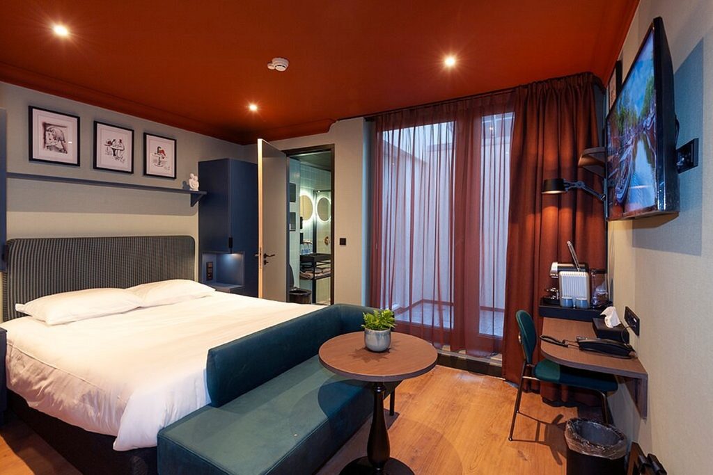 Comfortable modern hotel room with a double bed, stylish seating area and warm contemporary design at Hotel Nicolaas Witsen, Amsterdam