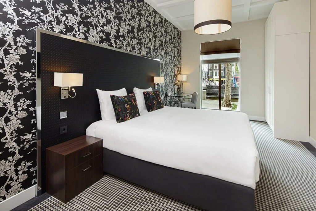 Bright modern double room with king-size bed and black-and-white floral wallpaper at Hotel Notting Hill, Amsterdam