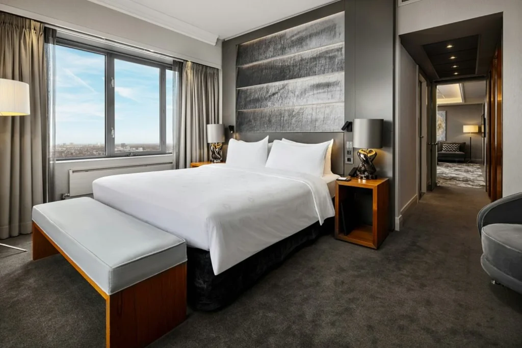 Spacious contemporary guest room with refined interiors and expansive windows overlooking the city at Hotel Okura Amsterdam, Amsterdam
