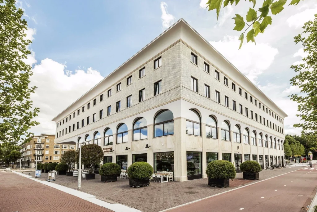 Modern hotel exterior with arched windows, outdoor seating and tree-lined surroundings at Hotel Twenty Eight, Amsterdam